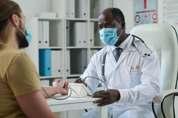 Érett Férfi Orvos Védő Maszkban Nézi Fiatal Beteget Miközben Ellenőrzi — Stock Fotó