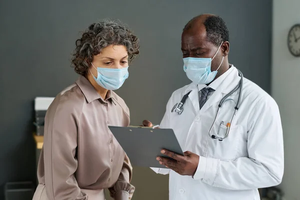 Reife Selbstbewusste Ärztin Maske Und Laborkittel Zeigt Auf Ärztliches Dokument — Stockfoto