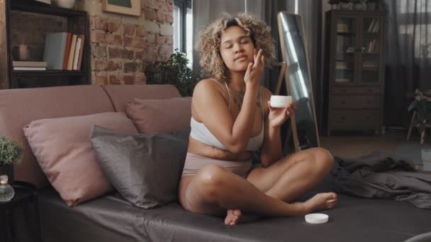 Jovem Afro Americana Sentada Cama Quarto Loft Manhã Aplicando Dabbing — Vídeo de Stock