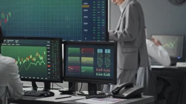 Siyahi adamın kulaklık taktığı, borsada borsa çizelgeleriyle çalıştığı, beyaz meslektaşlarının arka planda işlerini yaptıkları seçici bir odak noktası.
