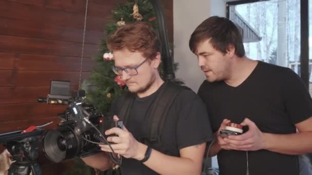 摄影师带着装有相机的背包 他的男性助手使用专业相机缩放控制器 — 图库视频影像