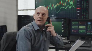 Çağdaş, olgun, Kafkas komisyoncu uzmanının telefonla konuşması, borsa ticaret sonuçları alması, cep telefonunu düşürmesi ve başarıyı kutlaması.