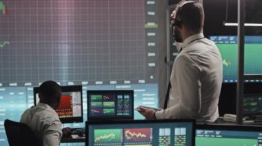 Borsa veya para birimi devalüasyonunu görünce hayal kırıklığına uğrayan iki aracı şirket uzmanı ekrana bakıyorlar.