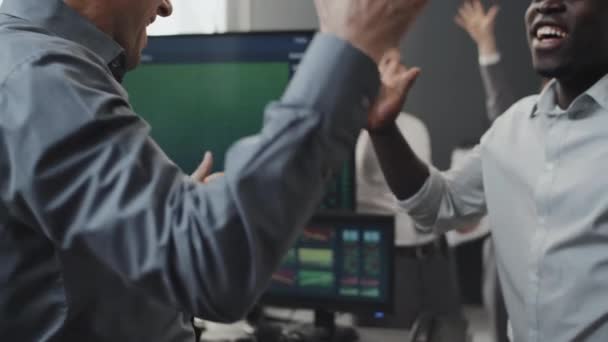 株式取引の結果を祝う証券会社で働く幸せな白人と黒人男性の遅い — ストック動画