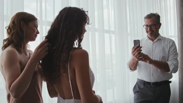 陽気な成熟した白人男性のスローモーション結婚式の日に彼の妻と娘の写真を撮る — ストック動画