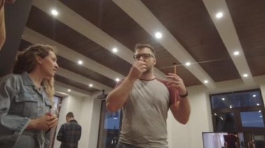 Gözlüklü düşük açılı yönetmen akşam film setinde kadın ve erkek aktörlerle konuşuyor.