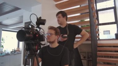 Profesyonel kamerayla film çeken iki erkek kameramanın alçak açılı görüntüsü.