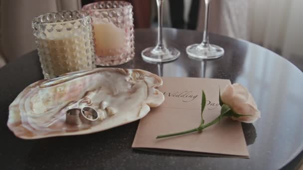 招待状 バラの花 キャンドル シャンパングラスと2つの結婚指輪とシェルの誰もまだ人生のショット — ストック動画