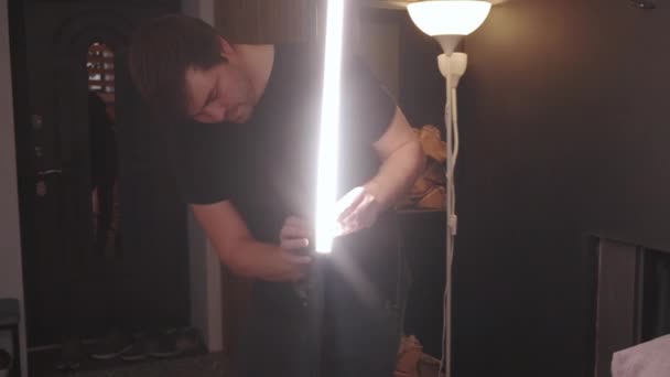 中髪の中髪の白人男性照明技術者が室内に設置された商業用ビデオ制作セットのステージライトを調整 — ストック動画