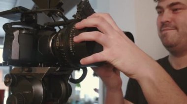 Erkek kameramanın düşük açılı yakın çekimi. Gündüz çekimleri sırasında film kamerasında lenslerini değiştiriyor.