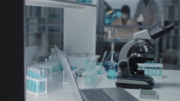Mikroskop Taşınabilir Bilgisayar Laboratuvar Masasındaki Tutacaklarda Sıvı Bulunan Test Tüpleri — Stok video