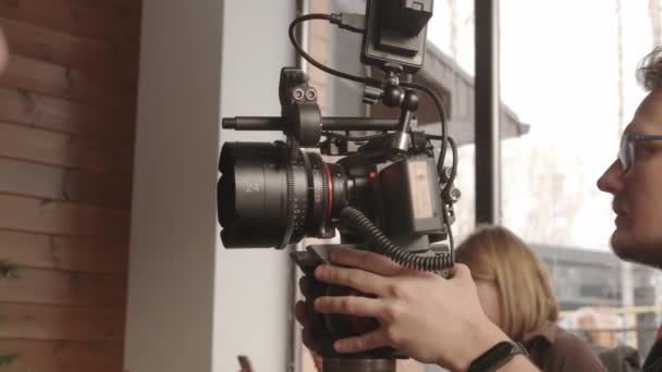 Стеження Молодим Чоловіком Окулярах Зйомка Професійній Відеокамері Приміщенні Вдень — стокове відео