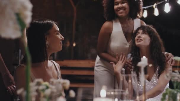 拍下了现代不同种族的女同性恋新婚夫妇坐在节日桌上和朋友们聊天的照片 — 图库视频影像