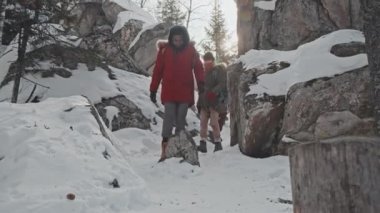 Kış günü dağdan aşağı inen sırt çantalı ve beyaz tenli üç aktif genç grup.