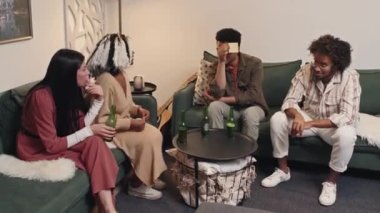 Etnik çeşitlilikte dört yetişkin erkek ve kadından oluşan bir grup, akşam partisinde tahmin oyunu oynuyorlar.