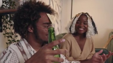 Alnında bira şişesi olan genç siyahi bir adam partide arkadaşlarıyla garip bir tahmin oyunu oynuyor.