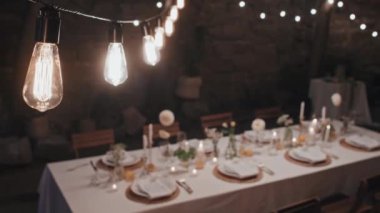 Seçici odak, modern restoranda düğün partisi için mum ve çiçeklerle süslenmiş uzun masa çekimleri yapılmayacak.