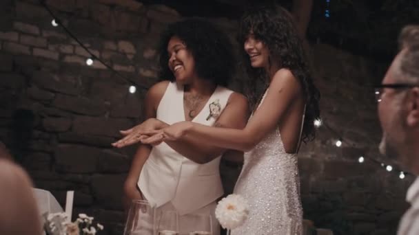 在晚会上 一对快乐的女同性恋夫妇吹嘘自己的结婚戒指 然后在晚会上与客人碰杯 — 图库视频影像