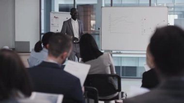 Modern siyahi iş adamının seçici odak noktası, meslektaşlarının veya yatırımcıların önünde sunuma başlıyor