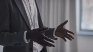 Kendine güvenen, gözlüklü ve zarif takım elbiseli genç Afro-Amerikan bir adam yeni iş projesinden bahsediyor.