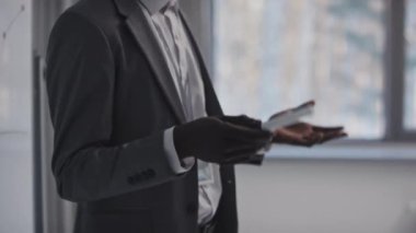 Genç Siyahi öğretim üyesi beyaz tahtada grafikler gösteren yeni bir iş projesine yatırım riskleri hakkında konuşuyor