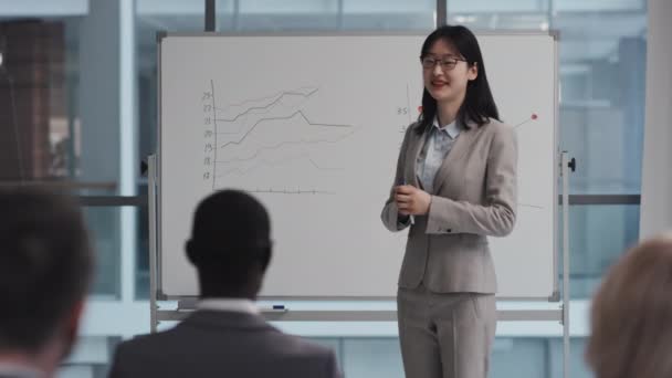 観客への統計について話すホワイトボードに立っている若いアジアの女性の選択的フォーカス中長期ショット — ストック動画