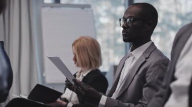 Genç siyahi bir adamın konferansa katılması ya da işletme fakültesinde seminere katılarak konuşmacıları dinlerken gazetelere bakması seçici bir odak noktası.