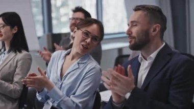 Modern etik çeşitlilikteki iş adamlarının yavaş çekimleri konuşmacıları alkışlıyor ve sunumu tartışıyorlar.