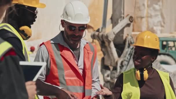 サングラスとハードハットを身に着けている成熟した白人のフォアマンは 労働者との作業計画を議論します 大理石の採石場の概念で働く日 — ストック動画