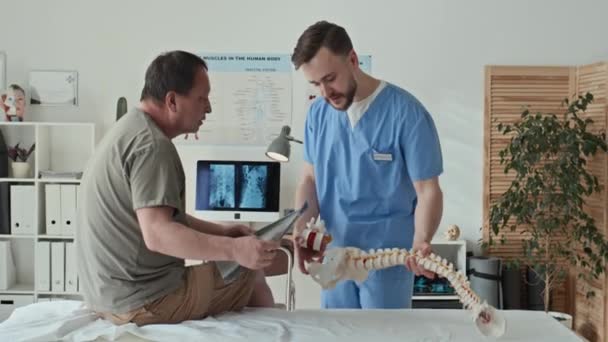 Therapeut Uniform Erklärt Dem Patienten Das Problem Der Wirbelsäule Und — Stockvideo