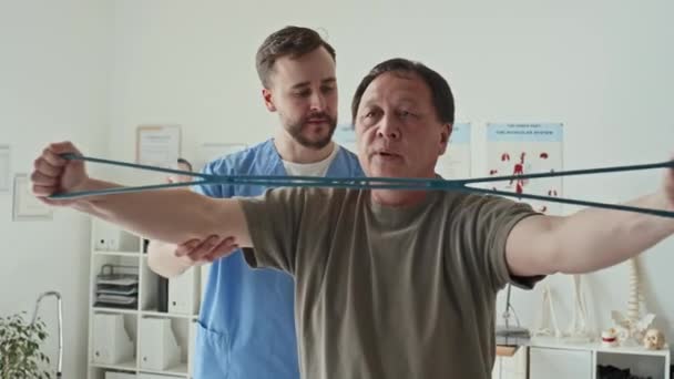 Asiatische Reife Patiententraining Mit Gummiband Während Seiner Rehabilitation Krankenhaus Zusammen — Stockvideo
