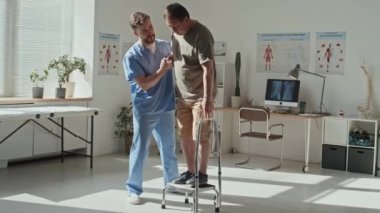 Üniformalı genç doktor hastanedeki rehabilitasyonu sırasında basamakta duran hastaya yardım ediyor.