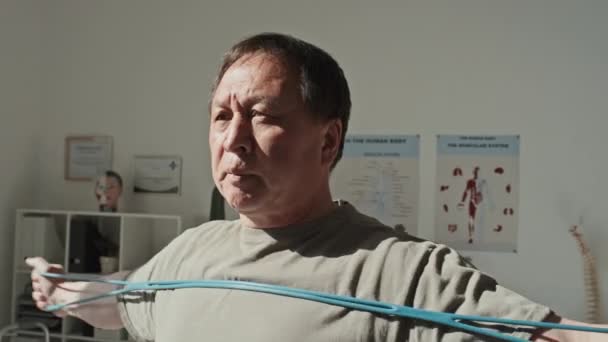 Азіатський Зрілий Пацієнт Має Гумову Стрічку Тренує Язи Рук Стоячи — стокове відео