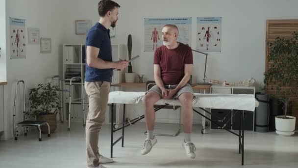 Junger Arzt Stellt Krankenhaus Fragen Patienten Und Macht Sich Notizen — Stockvideo