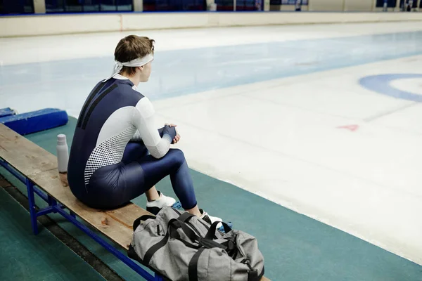 현대식 경기장 안에서 얼음장 벤치에 쉬면서 스피드 스케이팅 유니폼을 스포츠맨의 — 스톡 사진