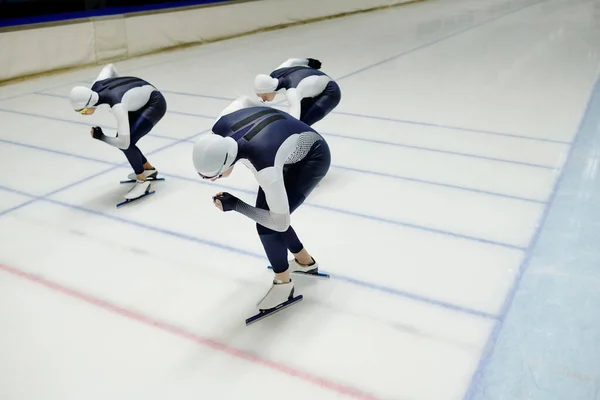 Three Young Sportsmen Sports Uniform Skates Bending Forwards While Sliding — Stock Photo, Image