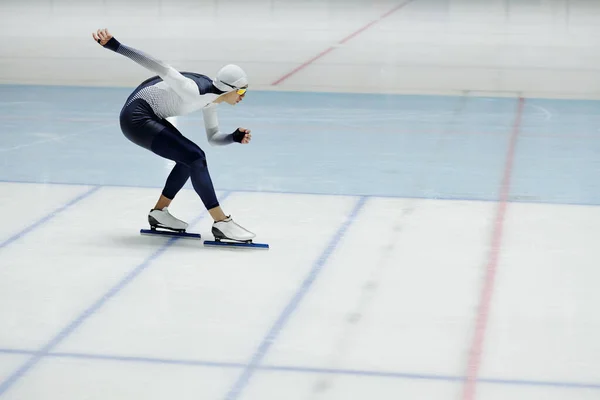 年轻的速滑选手 腿弯曲在膝上 右臂在后弯向前伸展 同时在比赛中滑下冰场 — 图库照片