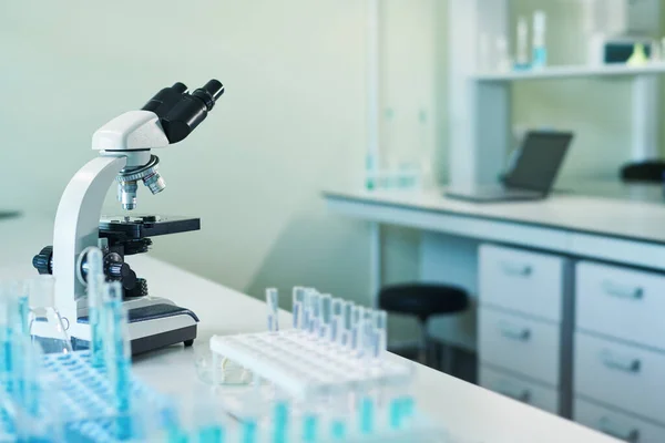 科研实验室或临床实验室的内部 在研究人员的工作场所装有蓝色液体物质的显微镜和瓶 — 图库照片