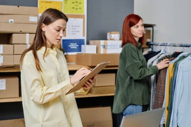 Elinde belgesi olan genç esmer kadın, yeni sıcak giysilere ihtiyaç duyan insanların listesini inceliyor.