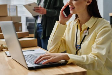 Sarı tişörtlü genç bayan gönüllülerin yakın plan fotoğrafları. İnternetteki ve telefondaki insanlara danışarak dizüstü bilgisayarın önünde oturuyorlar.