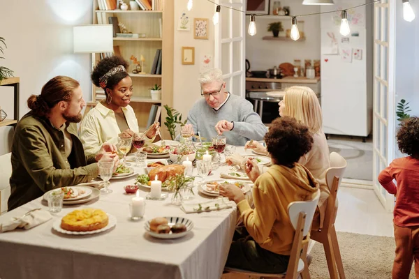 Suuren Kulttuurienvälisen Perheen Jäsenet Istuvat Kommunikoivat Tarjoilupöydän Mukaan Syödessään Kotitekoista — kuvapankkivalokuva