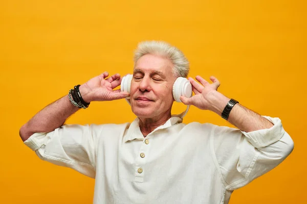 Ευτυχισμένος Ηλικιωμένος Άνδρας Λευκό Πουκάμισο Αγγίζοντας Ακουστικά Απολαμβάνοντας Μουσική Χαλάρωσης — Φωτογραφία Αρχείου