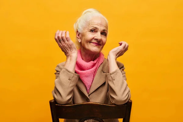 Starsza Sceptyczna Kobieta Siedząca Krześle Drewnianym Oparciem Przed Kamerą Izolacji — Zdjęcie stockowe