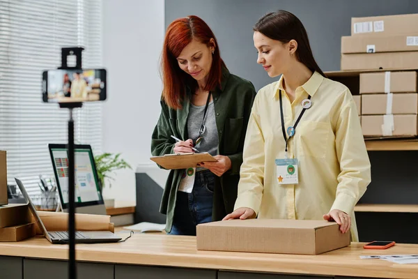 Young Volunteer Packed Parcel Standing Desk Next Her Colleague Document — Stock Photo, Image