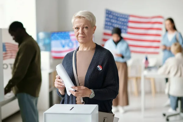 Reife Blonde Bürgerin Blickt Die Kamera Während Sie Der Wahlurne — Stockfoto