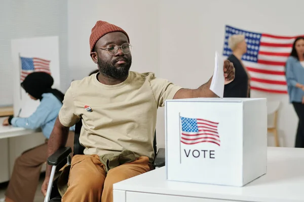 Молодой Афроамериканец Инвалидностью Сидит Инвалидном Кресле Кладет Избирательный Бюллетень Коробку — стоковое фото