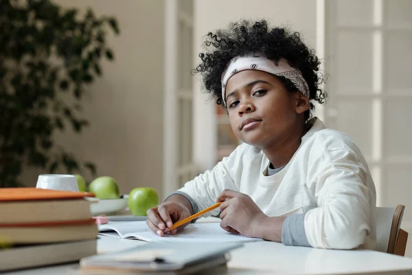 Söt Afroamerikansk Skolpojke Med Penna Tittar Kameran Medan Sitter Vid — Stockfoto