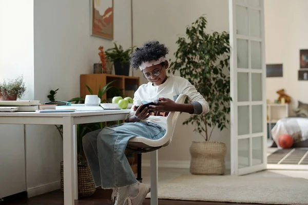 Glücklicher Jugendlicher Schüler Freizeitkleidung Mit Smartphone Während Wohnzimmer Schreibtisch Sitzt — Stockfoto