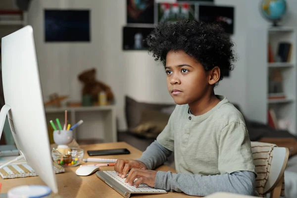 Allvarlig Skolpojke Som Sitter Framför Datorskärmen Vardagsrummet Och Skriver Tangentbordet — Stockfoto