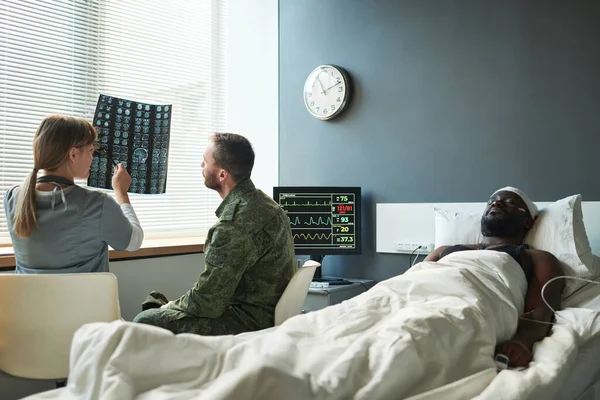 Ung Läkare Som Förklarar Detaljer Hjärnskanning Skadad Patient Till Soldat — Stockfoto
